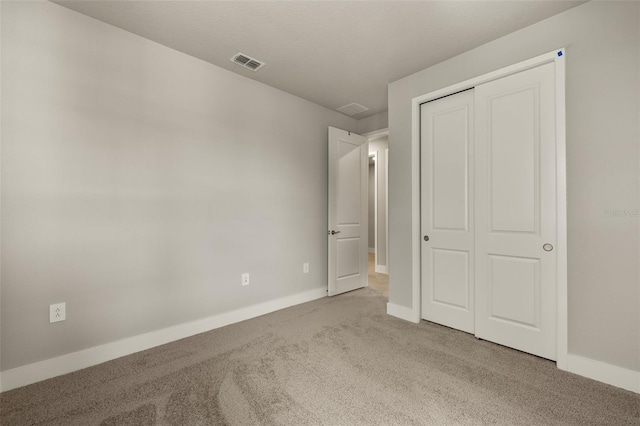 unfurnished bedroom featuring light colored carpet and a closet