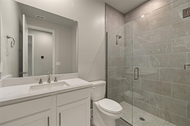 bathroom featuring vanity, toilet, and a shower with shower door