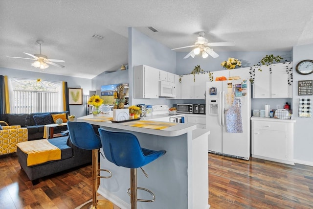 kitchen with dark wood-type flooring, a textured ceiling, lofted ceiling, white appliances, and white cabinets