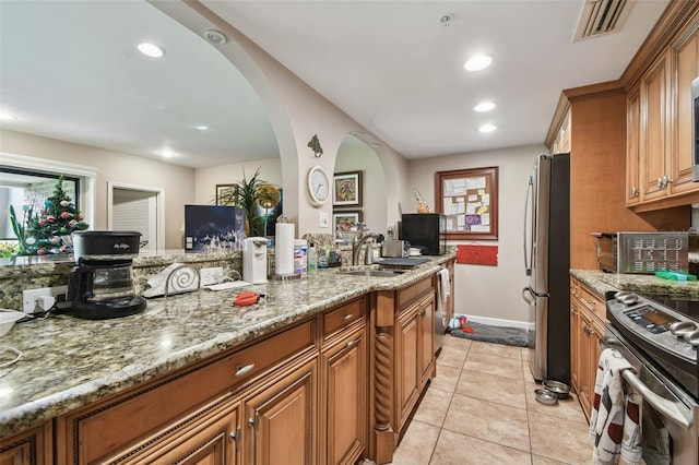 kitchen featuring light stone counters, sink, light tile patterned floors, and stainless steel appliances