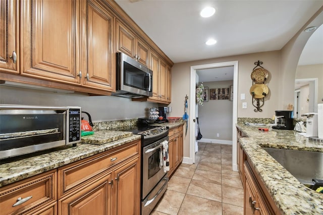 kitchen with light stone counters, light tile patterned floors, and stainless steel appliances