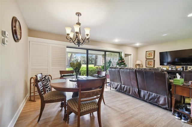 dining space with light wood-type flooring and an inviting chandelier