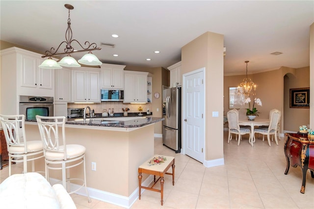 kitchen with hanging light fixtures, stainless steel appliances, dark stone counters, decorative backsplash, and white cabinets