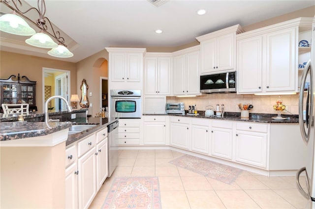 kitchen with decorative backsplash, stainless steel appliances, sink, white cabinetry, and hanging light fixtures