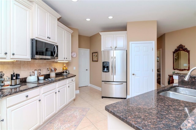 kitchen with sink, decorative backsplash, light tile patterned floors, appliances with stainless steel finishes, and white cabinetry