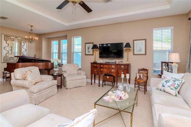 tiled living room featuring ceiling fan with notable chandelier and a tray ceiling