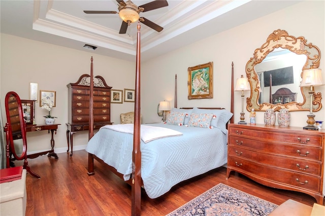 bedroom featuring a raised ceiling, ceiling fan, dark hardwood / wood-style floors, and ornamental molding