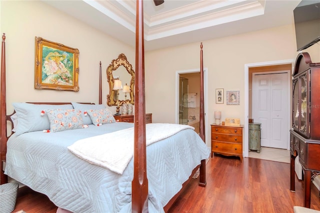 bedroom featuring ensuite bath, ornamental molding, a raised ceiling, ceiling fan, and dark hardwood / wood-style floors