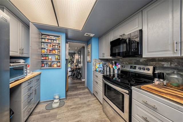 kitchen with gray cabinetry, light hardwood / wood-style flooring, tasteful backsplash, butcher block countertops, and stainless steel appliances