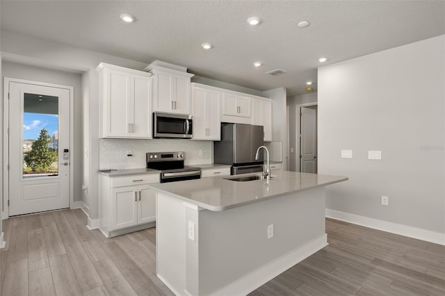 kitchen featuring sink, white cabinetry, a center island with sink, stainless steel appliances, and backsplash