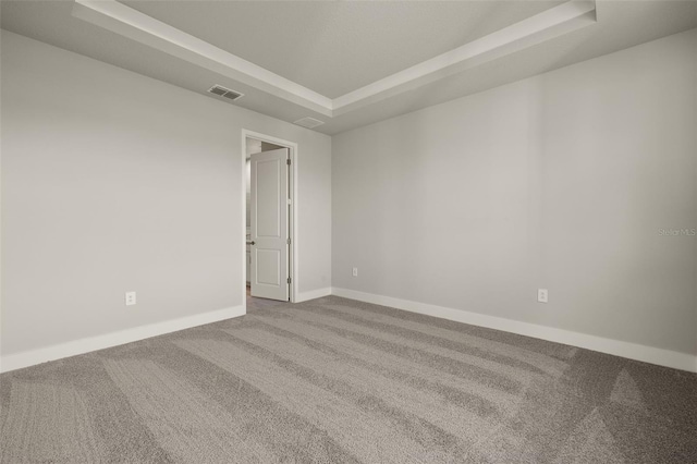 unfurnished room with a tray ceiling and carpet floors