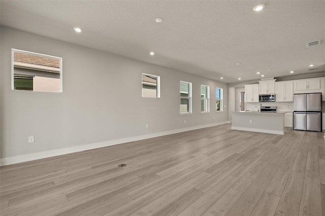 unfurnished living room featuring light hardwood / wood-style floors and a textured ceiling