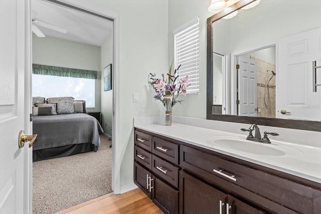 bathroom with walk in shower, wood-type flooring, vanity, and ceiling fan