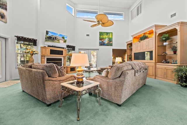 living room featuring dark colored carpet, a high ceiling, and ceiling fan