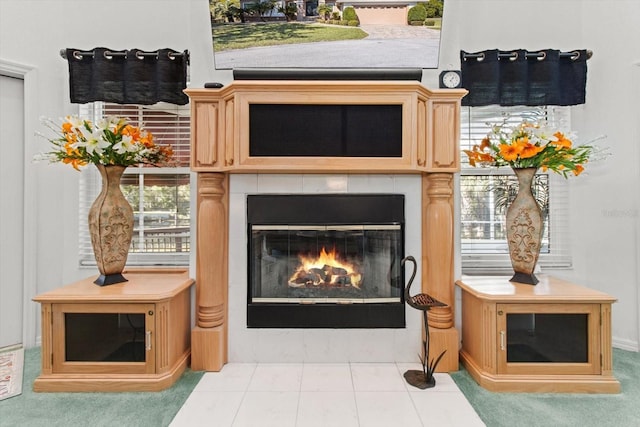 interior details featuring a tile fireplace and carpet flooring