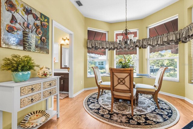 dining space featuring light hardwood / wood-style floors and an inviting chandelier