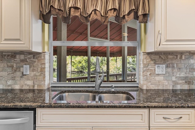 kitchen featuring dishwasher, decorative backsplash, dark stone countertops, and sink