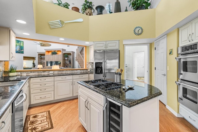 kitchen with ceiling fan, stainless steel appliances, wine cooler, white cabinets, and light wood-type flooring