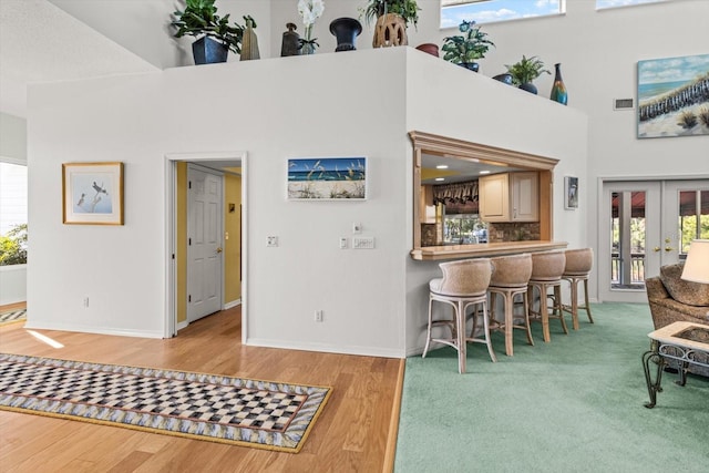 interior space featuring backsplash, french doors, a towering ceiling, and hardwood / wood-style floors