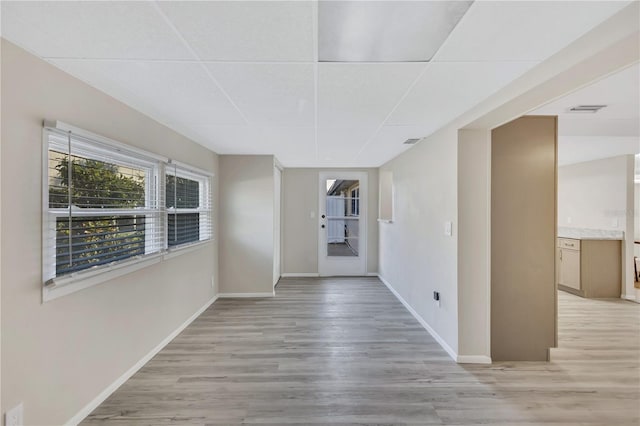 interior space with a drop ceiling and light hardwood / wood-style floors