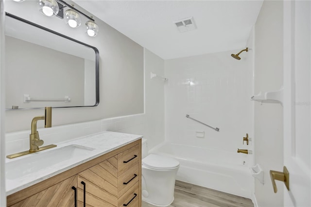 full bathroom with hardwood / wood-style flooring, vanity, toilet, and tiled shower / bath