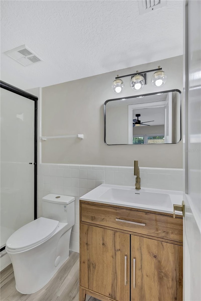 bathroom featuring vanity, a textured ceiling, ceiling fan, hardwood / wood-style flooring, and tile walls