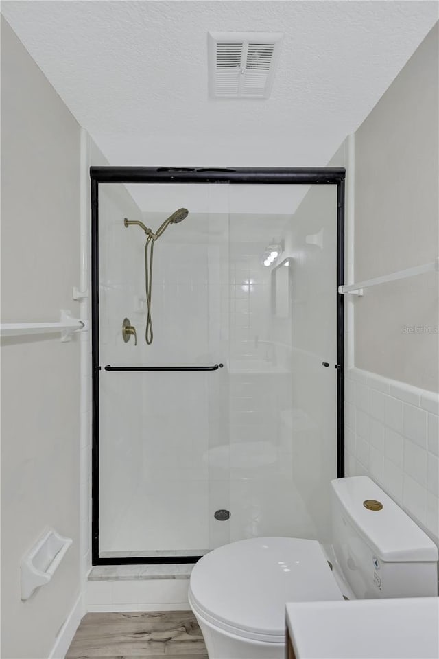 bathroom with a shower with door, wood-type flooring, and toilet