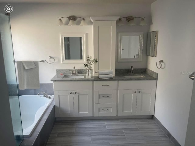 bathroom featuring tiled tub and vanity