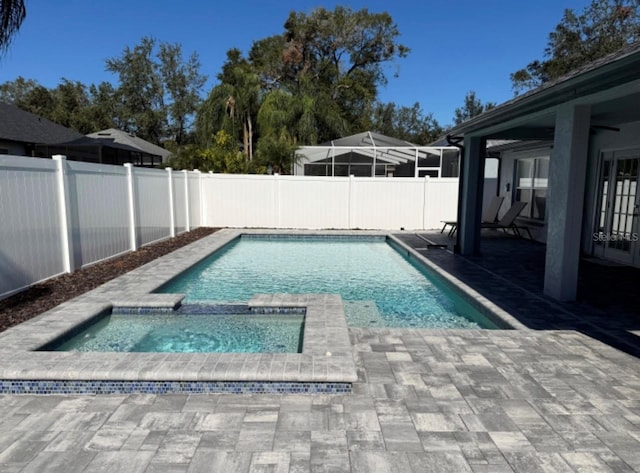 view of swimming pool featuring an in ground hot tub and a patio