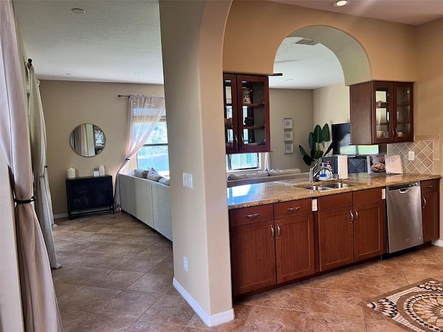 kitchen with dishwasher, sink, tasteful backsplash, light stone counters, and a textured ceiling