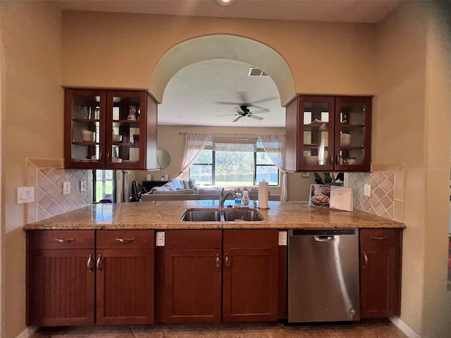 kitchen with ceiling fan, sink, light stone countertops, stainless steel dishwasher, and backsplash