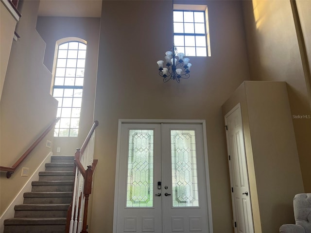 entryway featuring french doors, a high ceiling, and a chandelier