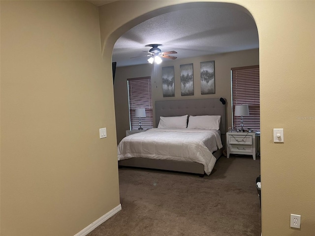 bedroom featuring ceiling fan, a textured ceiling, and dark colored carpet