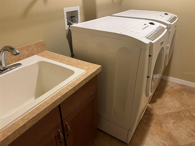 laundry area featuring light tile patterned flooring, cabinets, separate washer and dryer, and sink