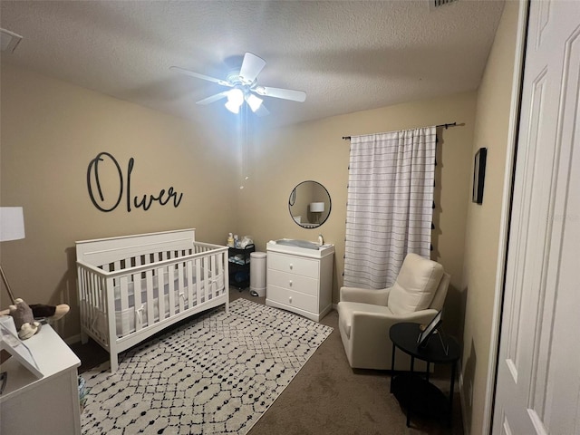 carpeted bedroom featuring ceiling fan, a crib, and a textured ceiling