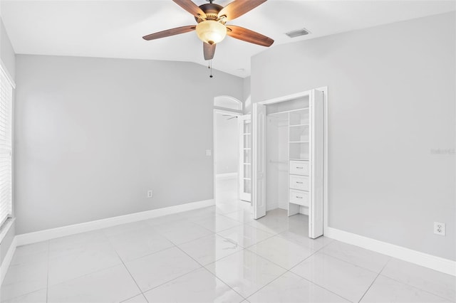 unfurnished bedroom with ceiling fan, a closet, light tile patterned floors, and lofted ceiling