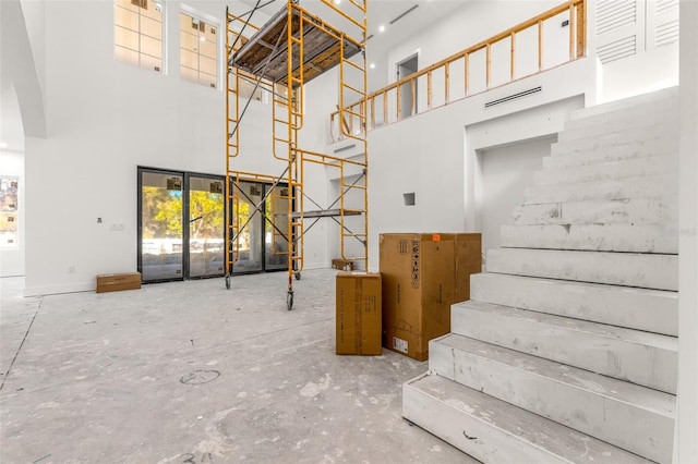 staircase with concrete flooring and a towering ceiling