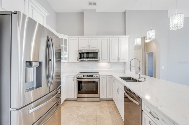 kitchen featuring white cabinets, sink, stainless steel appliances, and hanging light fixtures