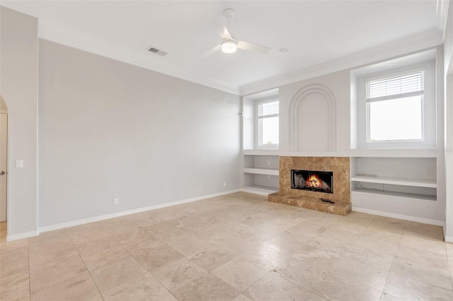 unfurnished living room featuring ceiling fan, a wealth of natural light, crown molding, and a premium fireplace