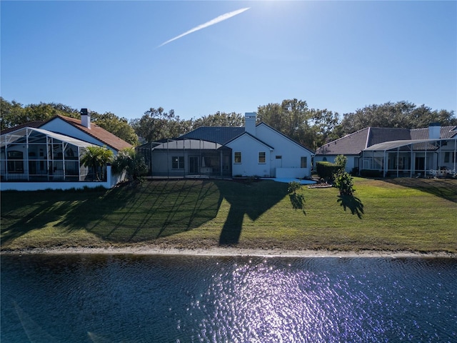 back of property featuring a lawn, glass enclosure, and a water view