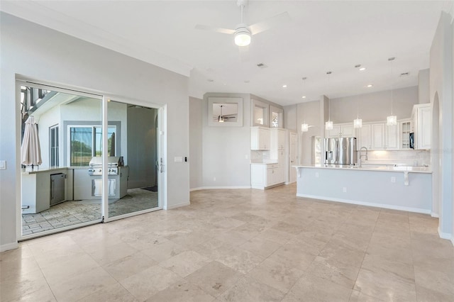 unfurnished living room featuring ceiling fan, light tile patterned flooring, and sink