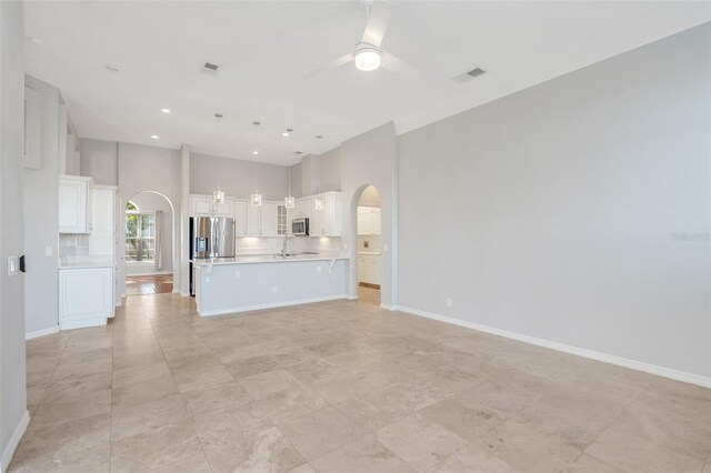 unfurnished living room with ceiling fan, sink, and a high ceiling