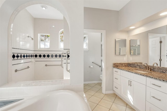 bathroom with tiled shower, tile patterned floors, vanity, and toilet