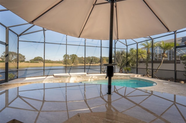 view of pool with glass enclosure, a patio area, and a water view