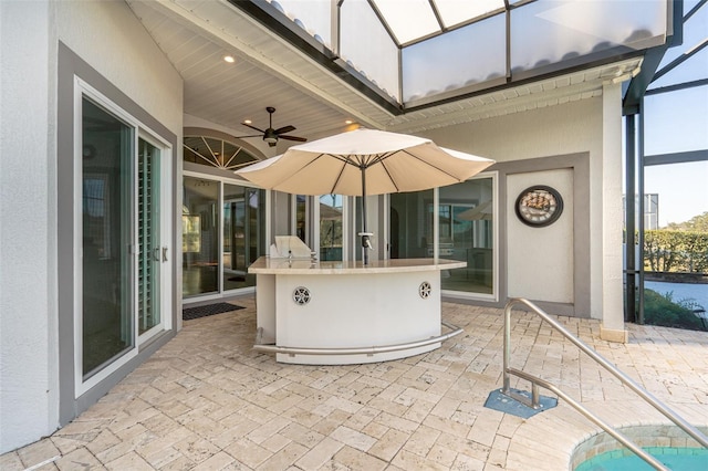 view of patio / terrace with glass enclosure, ceiling fan, and an outdoor bar