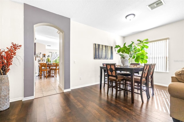 dining space with dark hardwood / wood-style floors and a textured ceiling