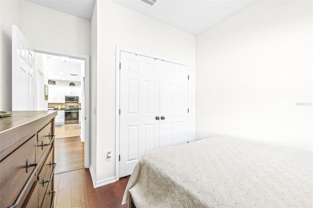 bedroom with dark hardwood / wood-style floors and a closet