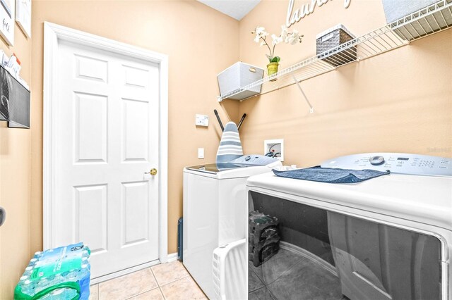 laundry area with washer and clothes dryer and light tile patterned floors