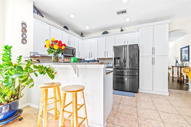 kitchen featuring white cabinetry, appliances with stainless steel finishes, a kitchen breakfast bar, and kitchen peninsula