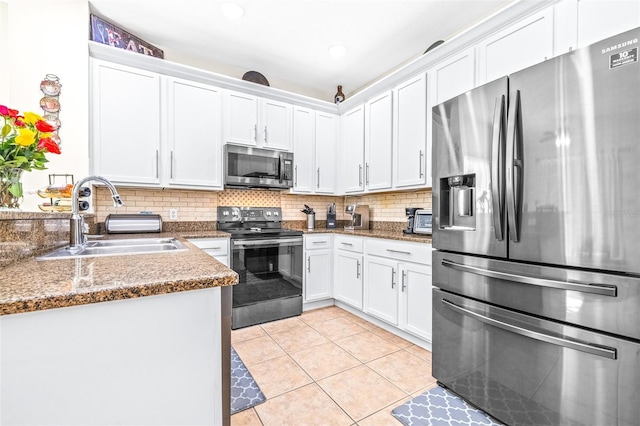 kitchen with sink, white cabinetry, dark stone countertops, stainless steel appliances, and light tile patterned flooring